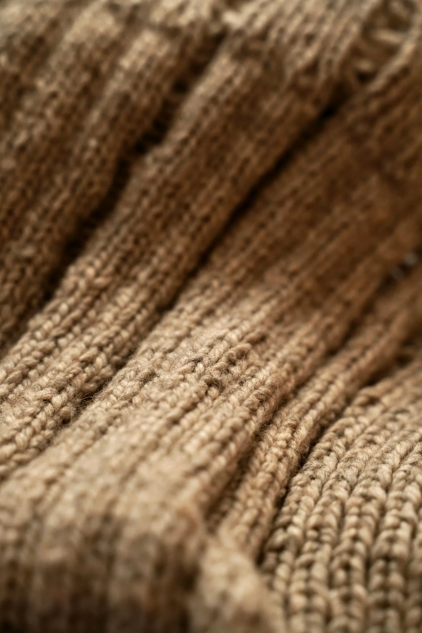 Close detail of beige knitted wool and its uneven fibers
